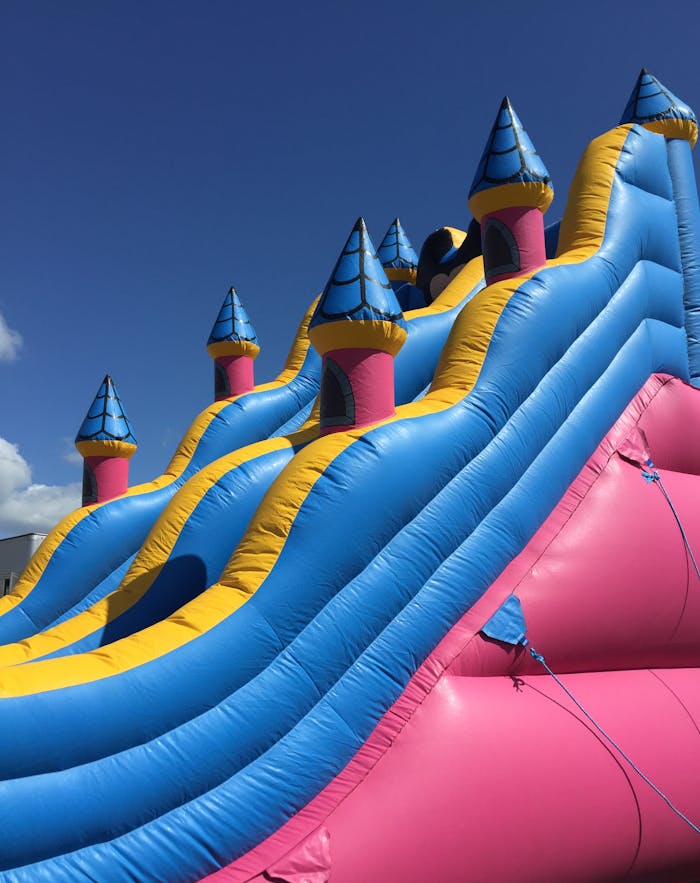 Services Bright inflatable slide with colorful turrets against a clear blue sky. Fun and playful atmosphere.